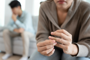 Esposa retirando aliança, marido atrás, sentado no sofá - divorcio judicial com filho menor