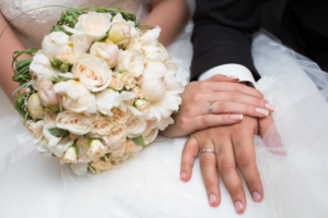 Noivos exibem alianças com uma mão sobre a outra, e buquê. Bens adquiridos antes do casamento podem ser divididos